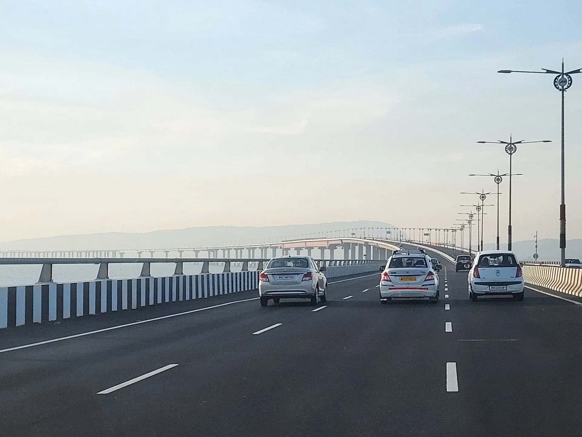 Cars driving along the six-lane deck of Atal Setu, with the bridge curving away across Mumbai harbour