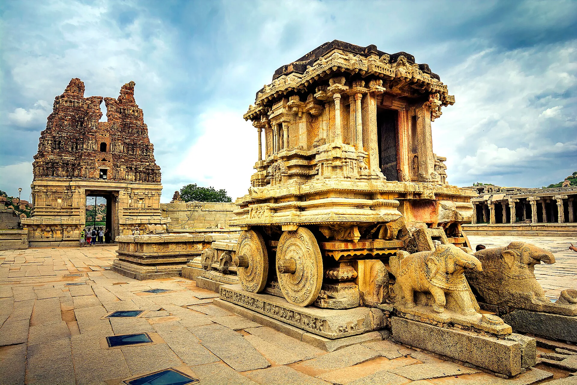 The carved stone chariot in the courtyard of the Vittala Temple at Hampi, with a temple gateway behind