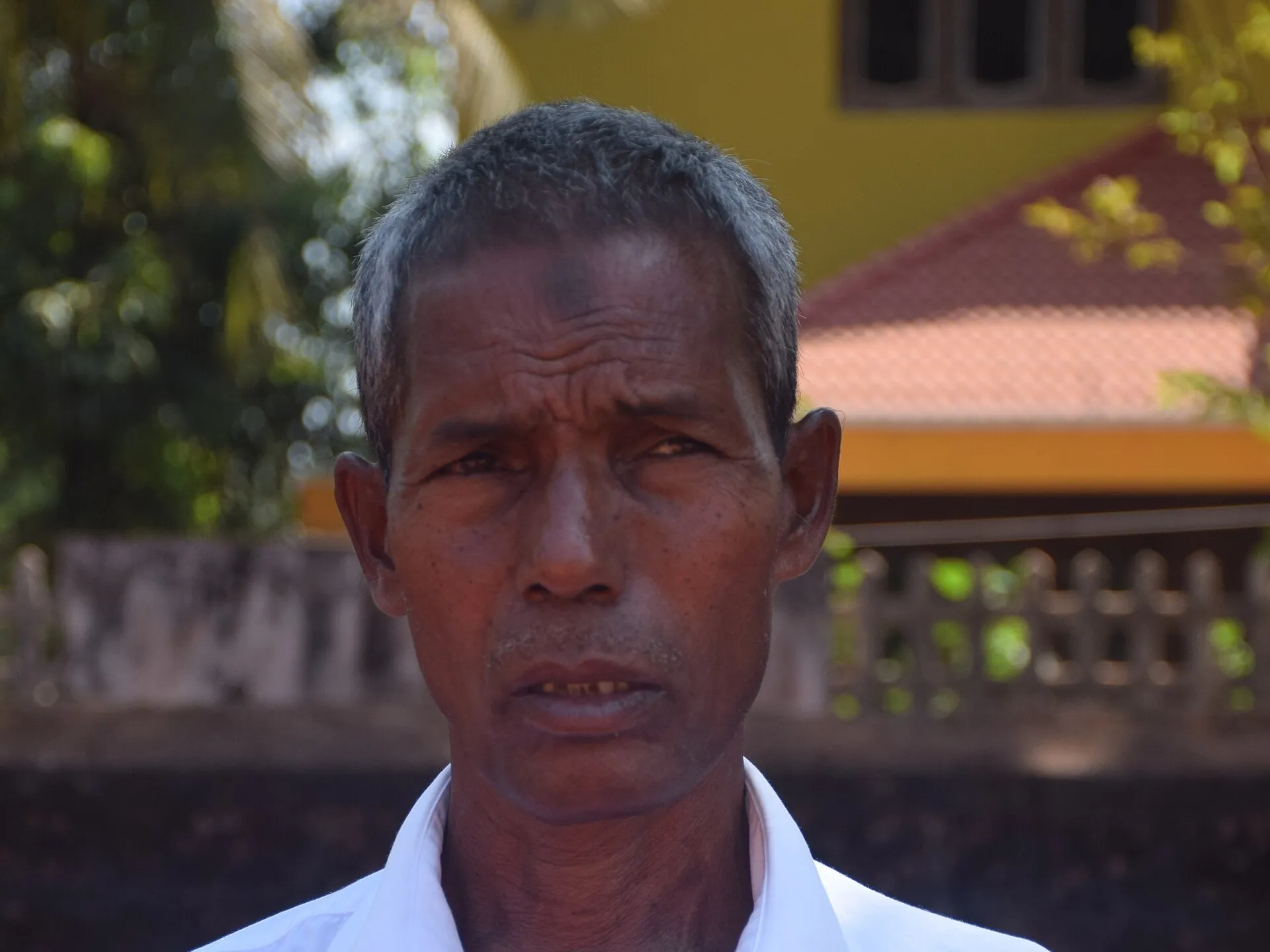 Harekala Hajabba standing outside a house in Karnataka, wearing a white shirt