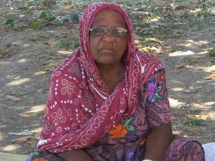 Hirabai Lobi seated outdoors in a printed sari and red headscarf