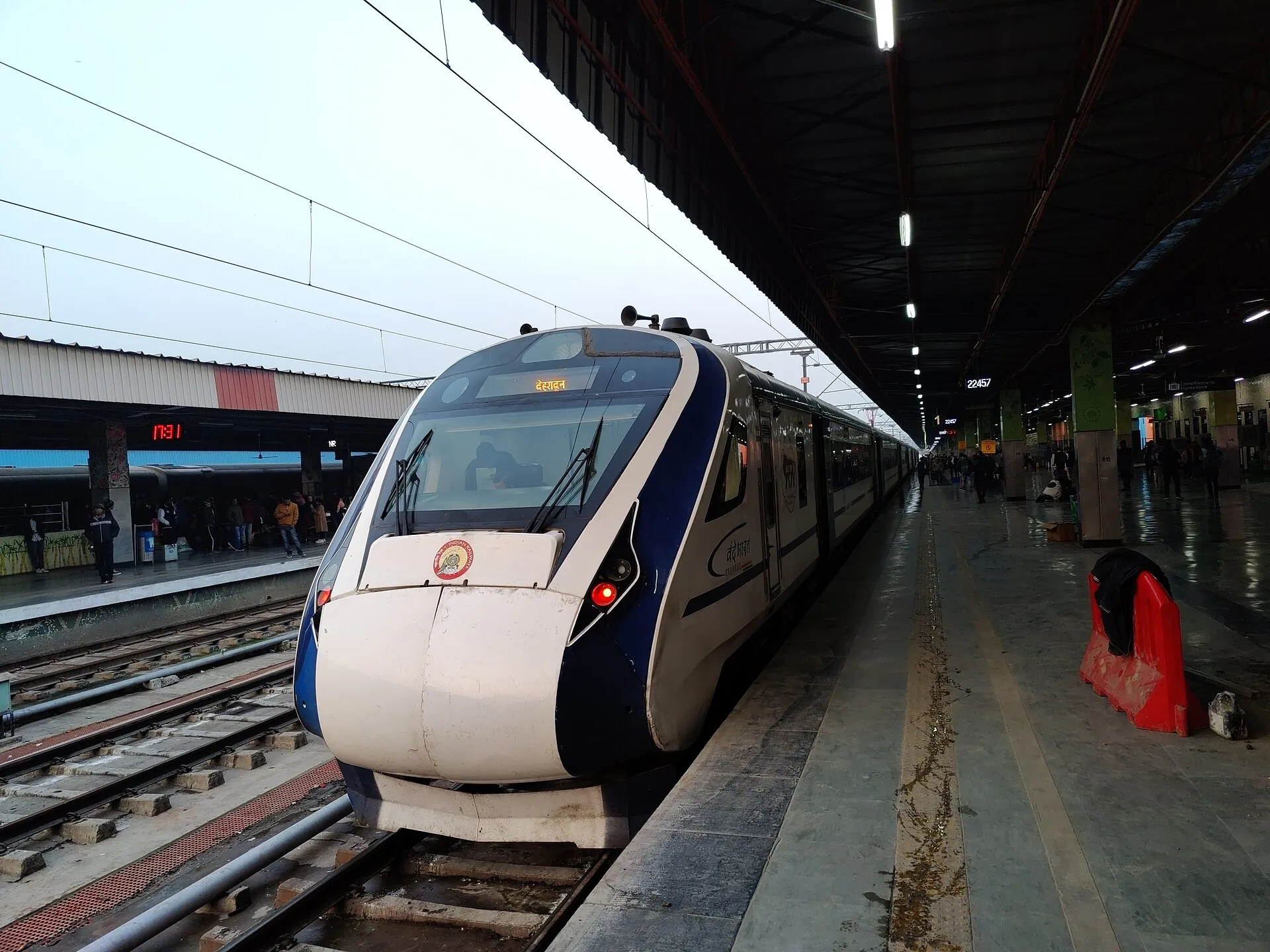 A white-and-blue Vande Bharat Express train waiting at a platform at Anand Vihar Terminal, Delhi