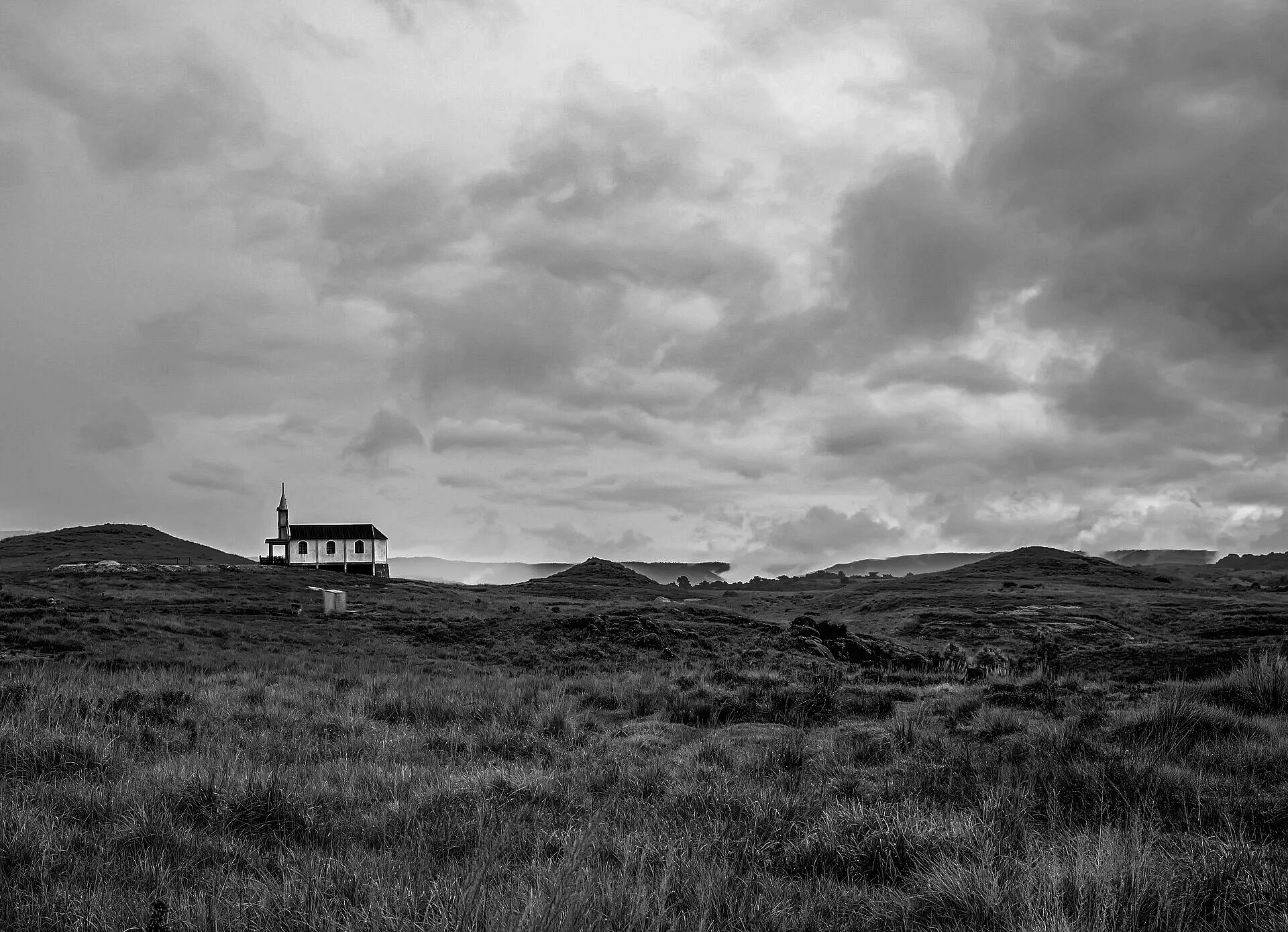Low storm clouds over grassy hills and a lone building near Mawsynram, Meghalaya